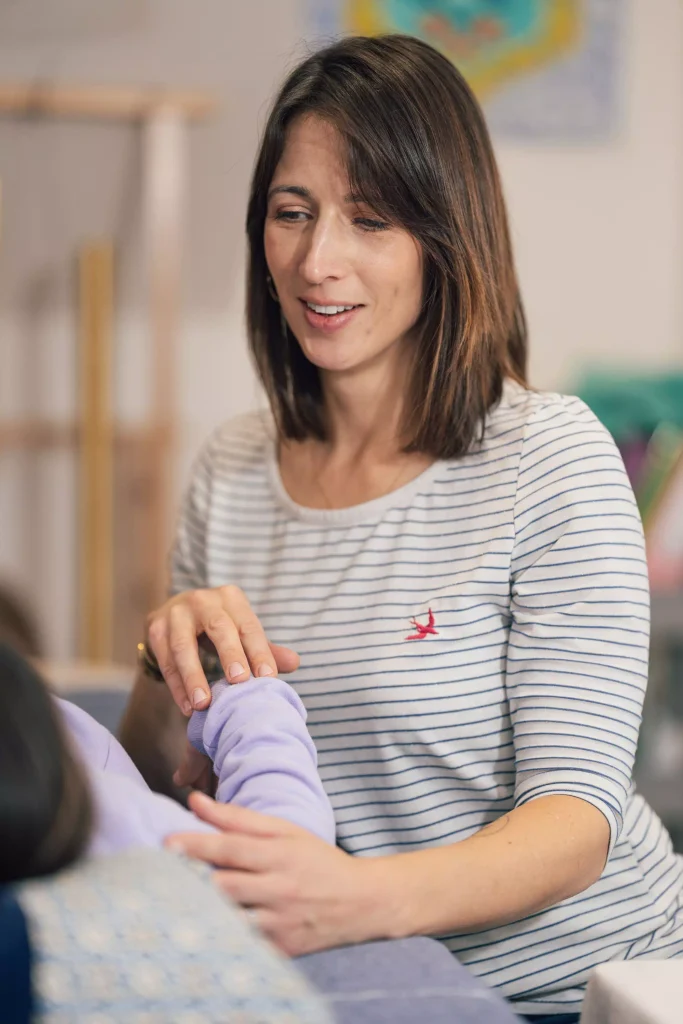 kinésiologue aidant un enfant assis.